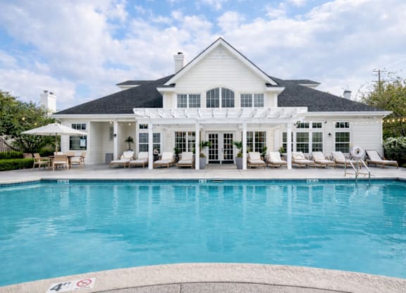 A large white house with a pool in front.