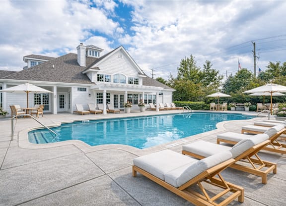 A large house with a pool and lounge chairs.