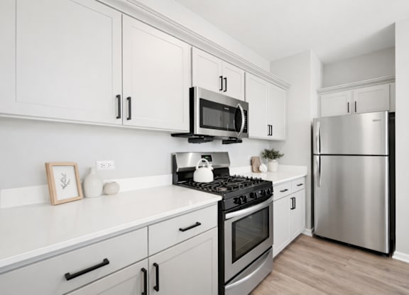 A modern kitchen with a stainless steel refrigerator and a black and silver stove top.