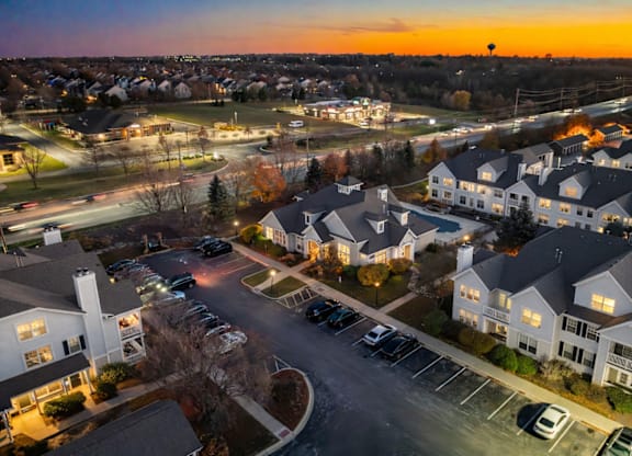 A sunset view of a residential area with houses and parked cars.