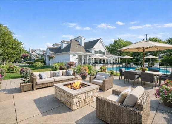 A patio with a fire pit and seating area in front of a house.