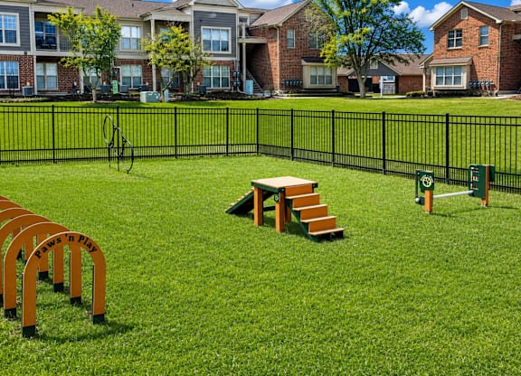 A playground with a slide, swings, and a seesaw in a grassy area.