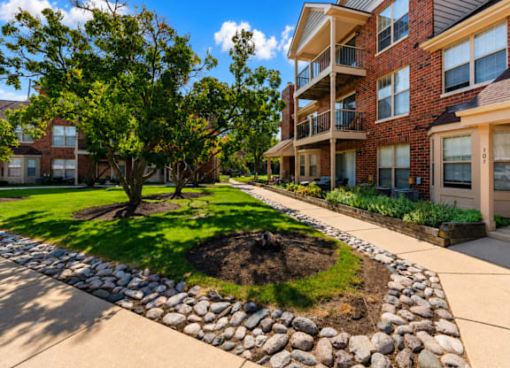 A tree in a grassy area in front of a building.