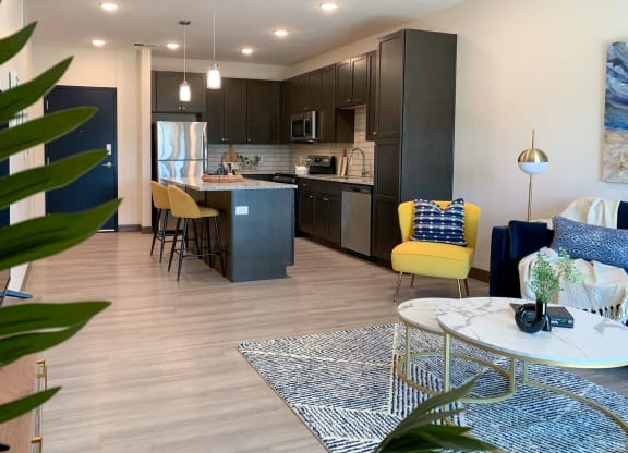 the view of the kitchen with dark cabinets from the corner of the living room