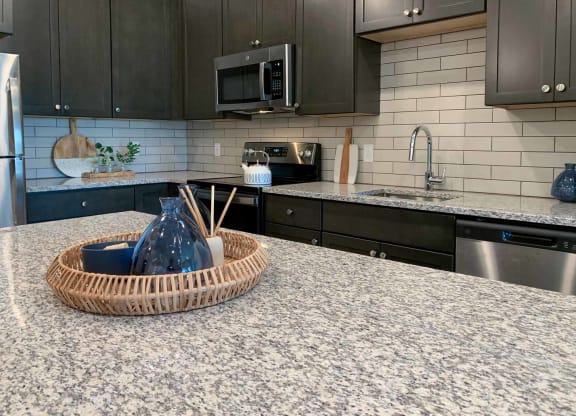 a decorative wicker tray on the granite counter top of the kitchen island