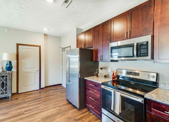 A kitchen with wooden cabinets and a stainless steel refrigerator.