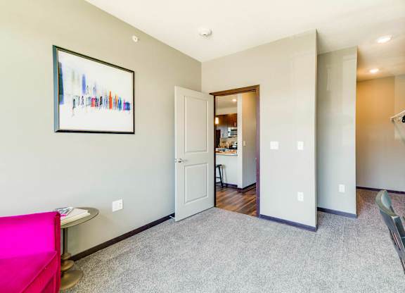A living room with a pink couch and a painting on the wall.