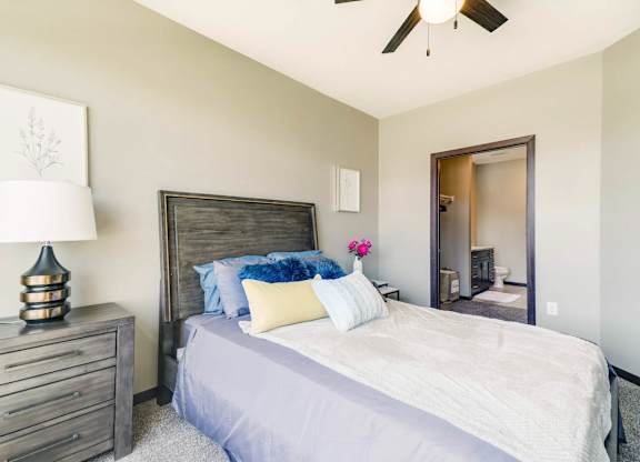 A bedroom with a bed, dresser, and ceiling fan.