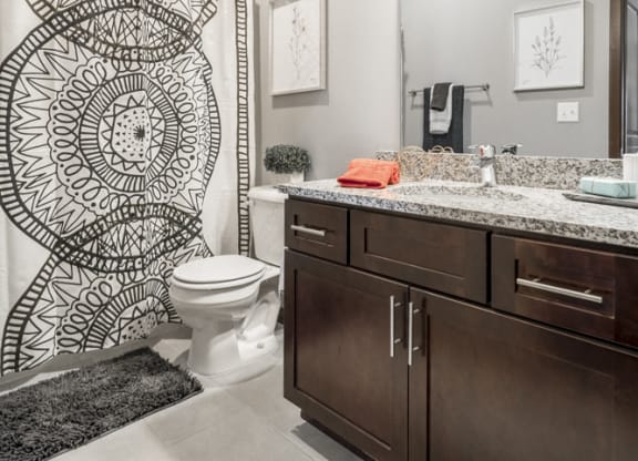 Bathroom with dark cabinetry and light granite countertops at 360 at Jordan West best new apartments West Des Moines IA 50266