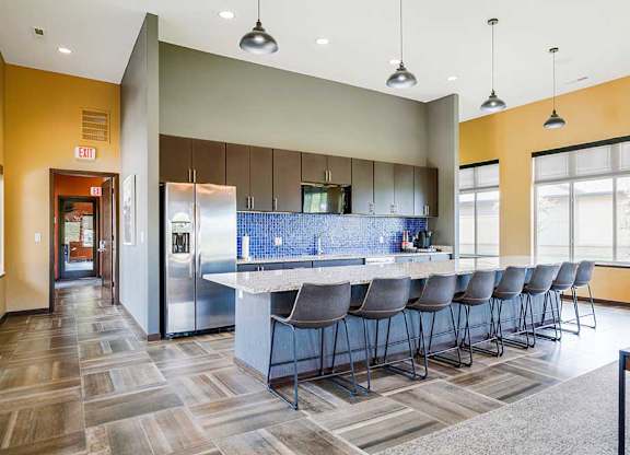 A kitchen in the clubhouse with an oversized island and several barstools.