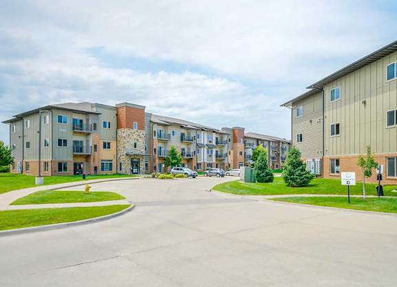 A brick and stone apartment building with professionally landscaped lawns surrounding it.