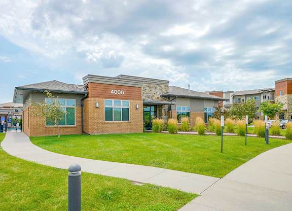 A modern clubhouse with a professionally landscaped green lawn.