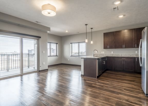 View from living room of kitchen and dining room with hardwood-style floors and balcony at 360 at Jordan West best new apartments West Des Moines IA 50266