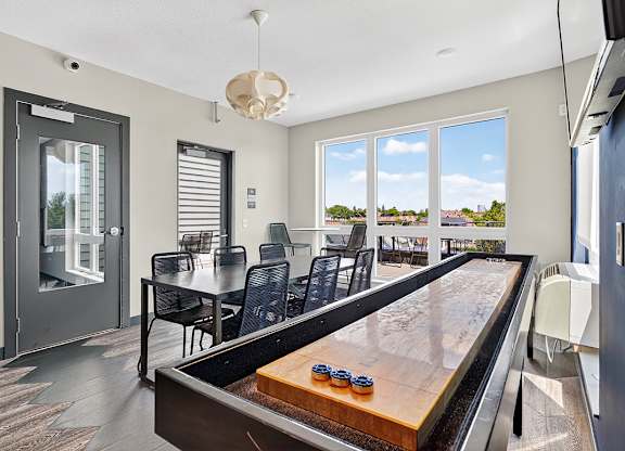 A shiny pool table is in the middle of a room with a glass door.