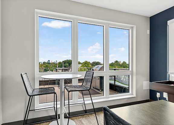 A room with a table and chairs in front of a large window.