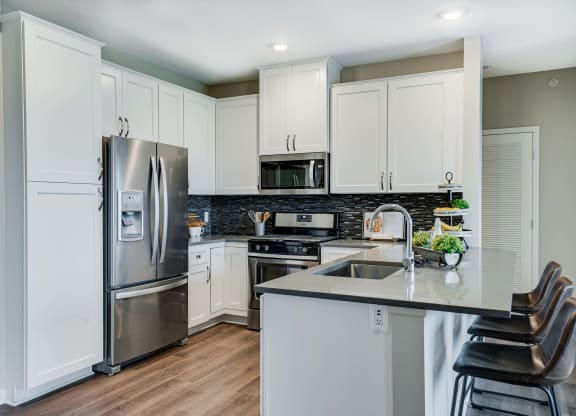 Premium kitchen featuring dark quartz countertops and white cabinetry in a two bedroom penthouse Princeton floor plan