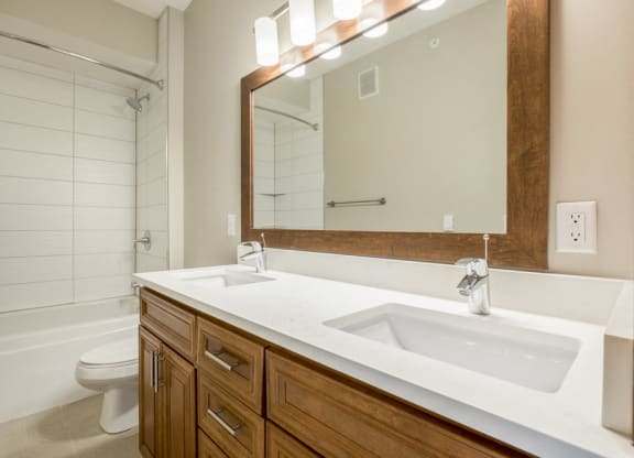 Dual sinks in bathroom with tiled tub in premium unit at Ascend at Woodbury new luxury apartments in Woodbury MN 55129