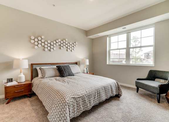 A bedroom with a large bed, a chair, and a lamp.