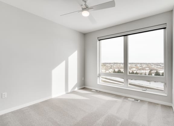 Spacious luxury bedroom with large window and ceiling fan at Aspire at CityPlace in Woodbury, Minnesota