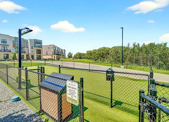Fenced dog park with waste station and open turf area, located within a pet-friendly apartment community.