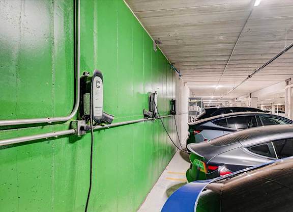 A parking garage with green walls and cars parked.