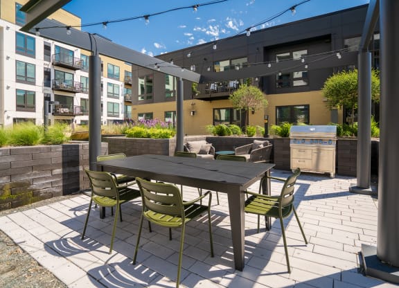 Outdoor lounging and cooking area with grill, table, and chairs at Aspire at Cityplace