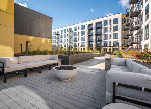 Outdoor seating area with couches and firepit in the courtyard at Aspire at CityPlace Woodbury