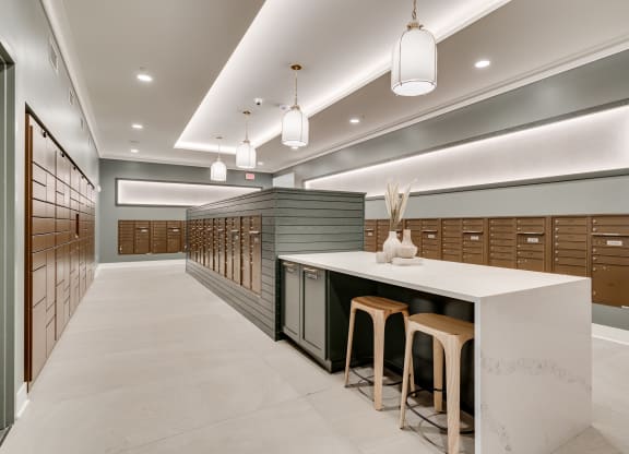 Mailroom lined with package lockers and mailboxes and island seating in the middle