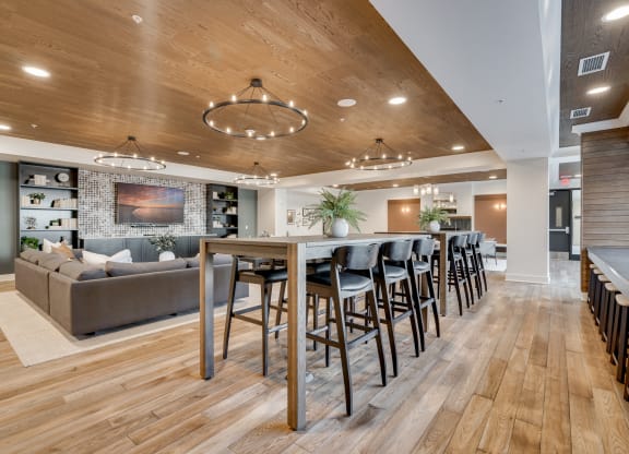Community room with table seating and large sectionals around a TV at Aspire