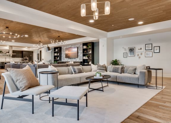 Community room with professional kitchen and large sectionals around a TV at Aspire