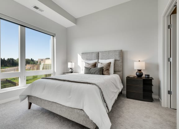 Furnished bedroom with high ceiling, large window and connected bathroom