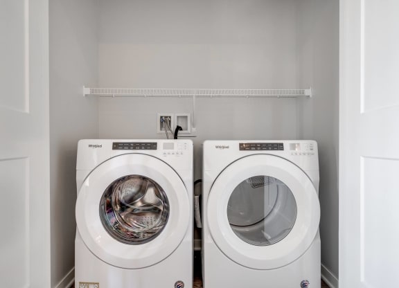 Side by side front loader washer and dryer in a laundry closet in two bedroom luxury apartment Woodbury MN 55125