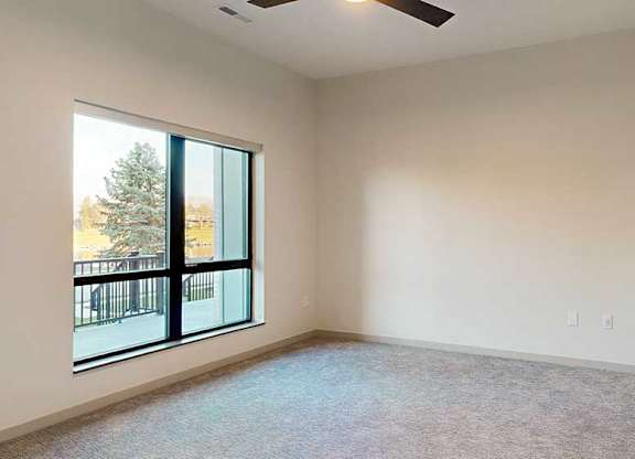 a bedroom with a large window and a ceiling fan