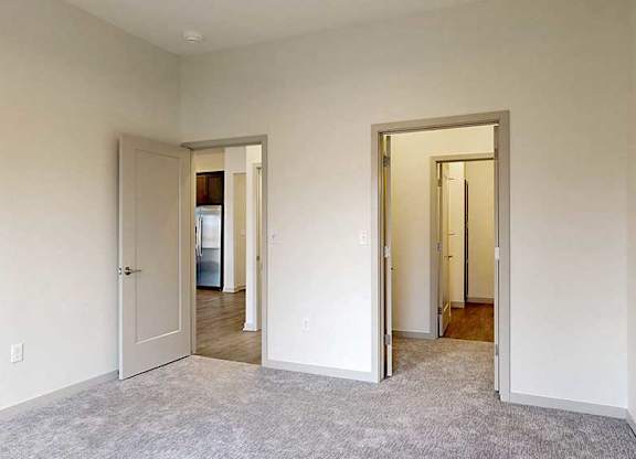a bedroom with a walk-through closet to the attached bathroom and a door to the living room