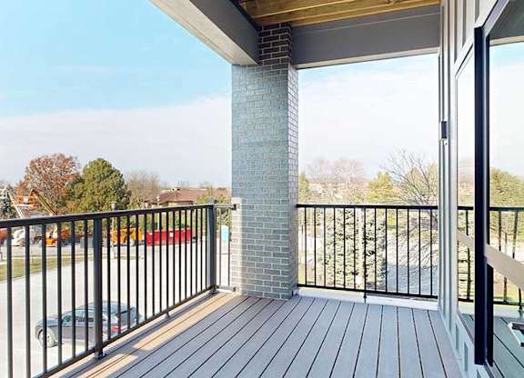 a balcony with a black metal railing and a brick pillar