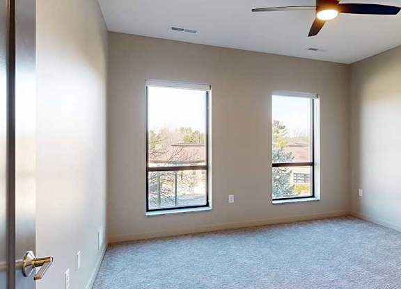 a bedroom with a carpeted floor and two windows