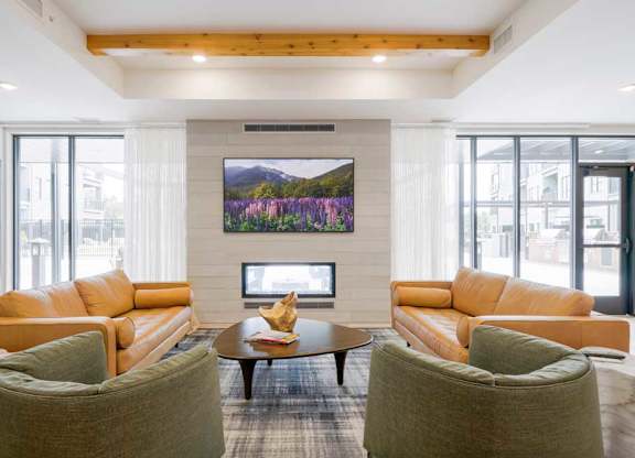 A clubroom with a TV lounge, two-way fireplace, and lounge seating.