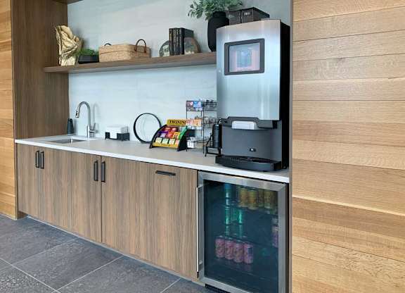 a coffee bar with an espresso machine, a mini fridge with drinks, and tea options in the front lobby