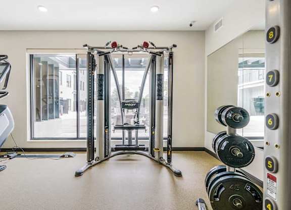 a 24-hour fitness center with a Smith machine and racks of weights