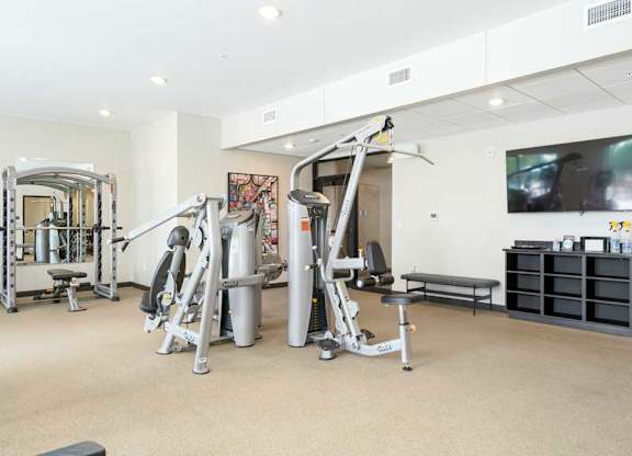 a 24-hour fitness center with several weight machines and a tv