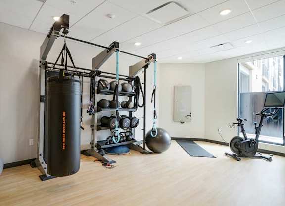 a 24-hour yoga & spin studio with a punching bag, pilates and yoga equipment, a bike, and an on-demand course mirror