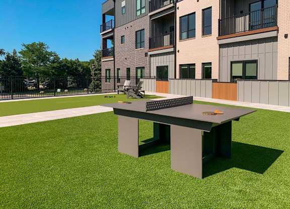 a modern ping pong table in a courtyard with turf grass
