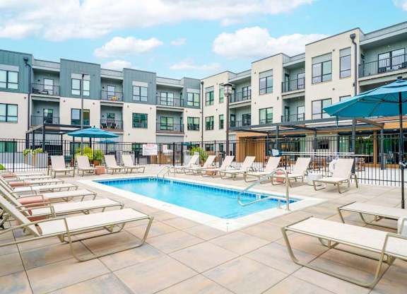 A lounge pool surrounded by several lounge chairs and umbrellas for shade.