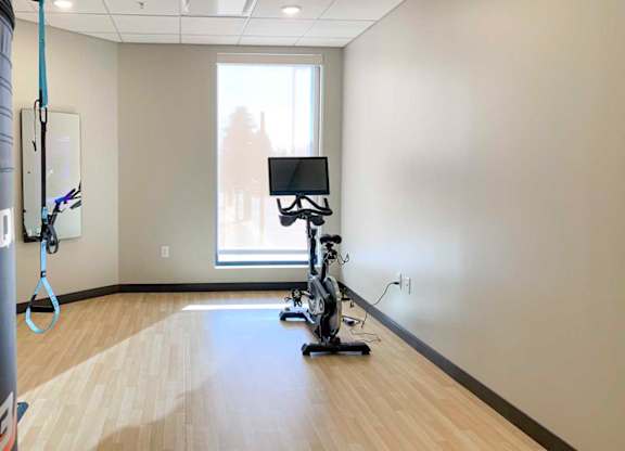 a  yoga and spin studio with an exercise bike in front of a window and interactive fitness mirror