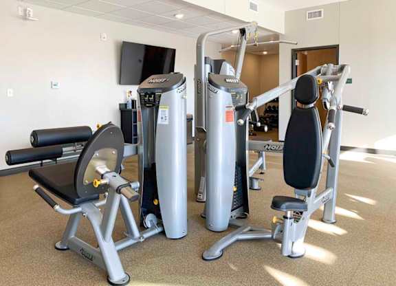 a fitness center with a variety of equipment including a weight machine, a leg press machine, and a rowing machine