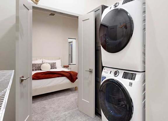a stacked washer and dryer inside a walk-in closet