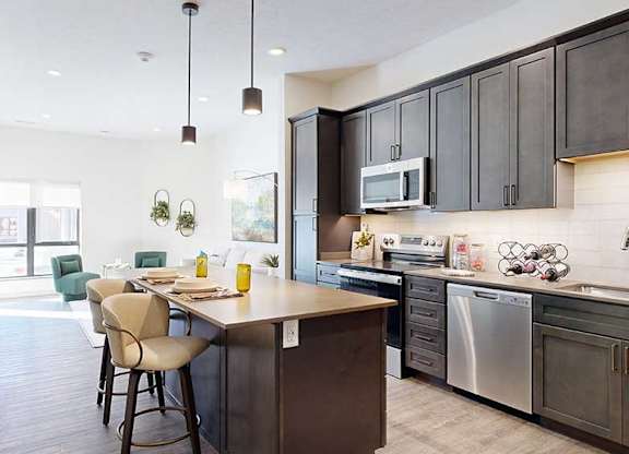a modern kitchen with a stainless steel appliances, quartz countertops, a light tile backsplash, dark wooden cabinets, and a large central island