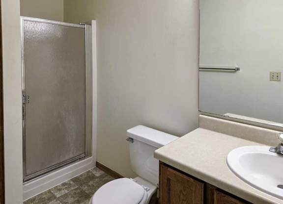 A bathroom with a sink, large mirror, and shower with a glass door.