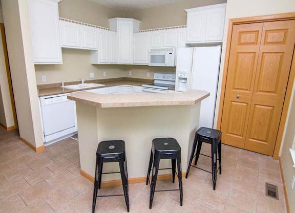 a kitchen with white cabinets, an island, and three stools