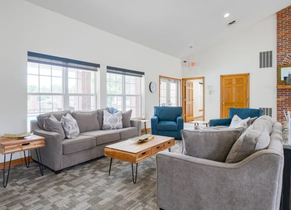 Lounging area in clubhouse with couches and chairs and a brick fireplace in the back